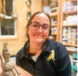 Young girl with glasses, smiling; Posing with clay artwork