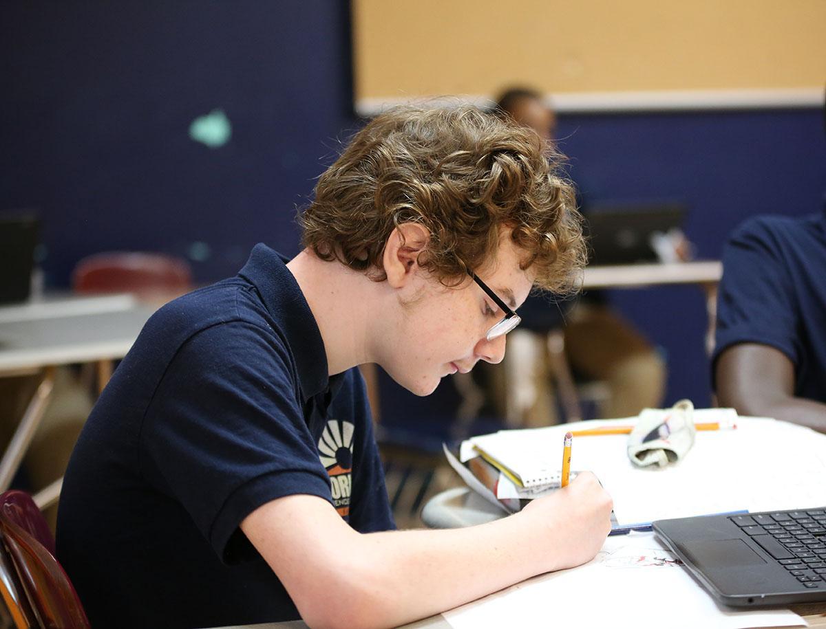 Student working on a notebook in a classroom.