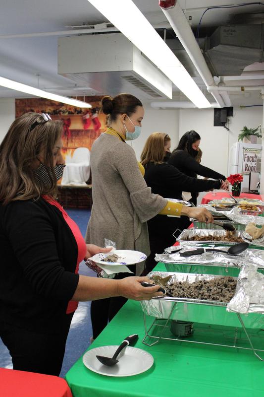 4 women walking down line of food table