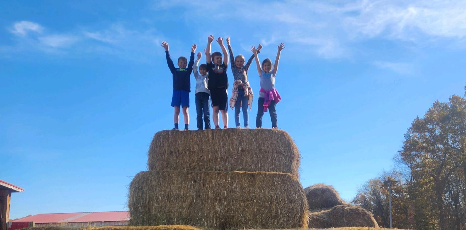 kids standing on hay bales