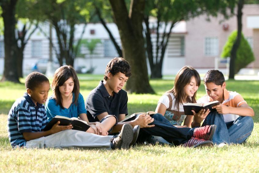 kids sitting in grass reading