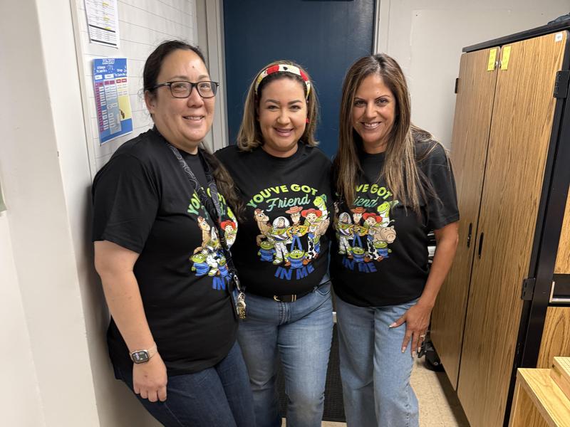 Three women wearing matching t-shirts standing together, smiling at the camera.