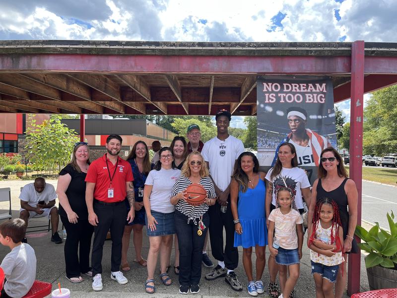 Dybantsa with Davis School staff alongside hanging banner