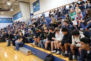 Incoming freshmen listen to first day orientation in the gym
