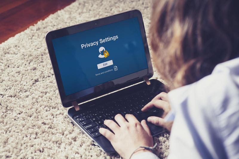 User adjusting privacy settings on a laptop displayed on a carpet.