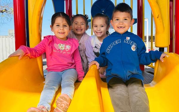 Three girls and a boy sitting on top of the slide