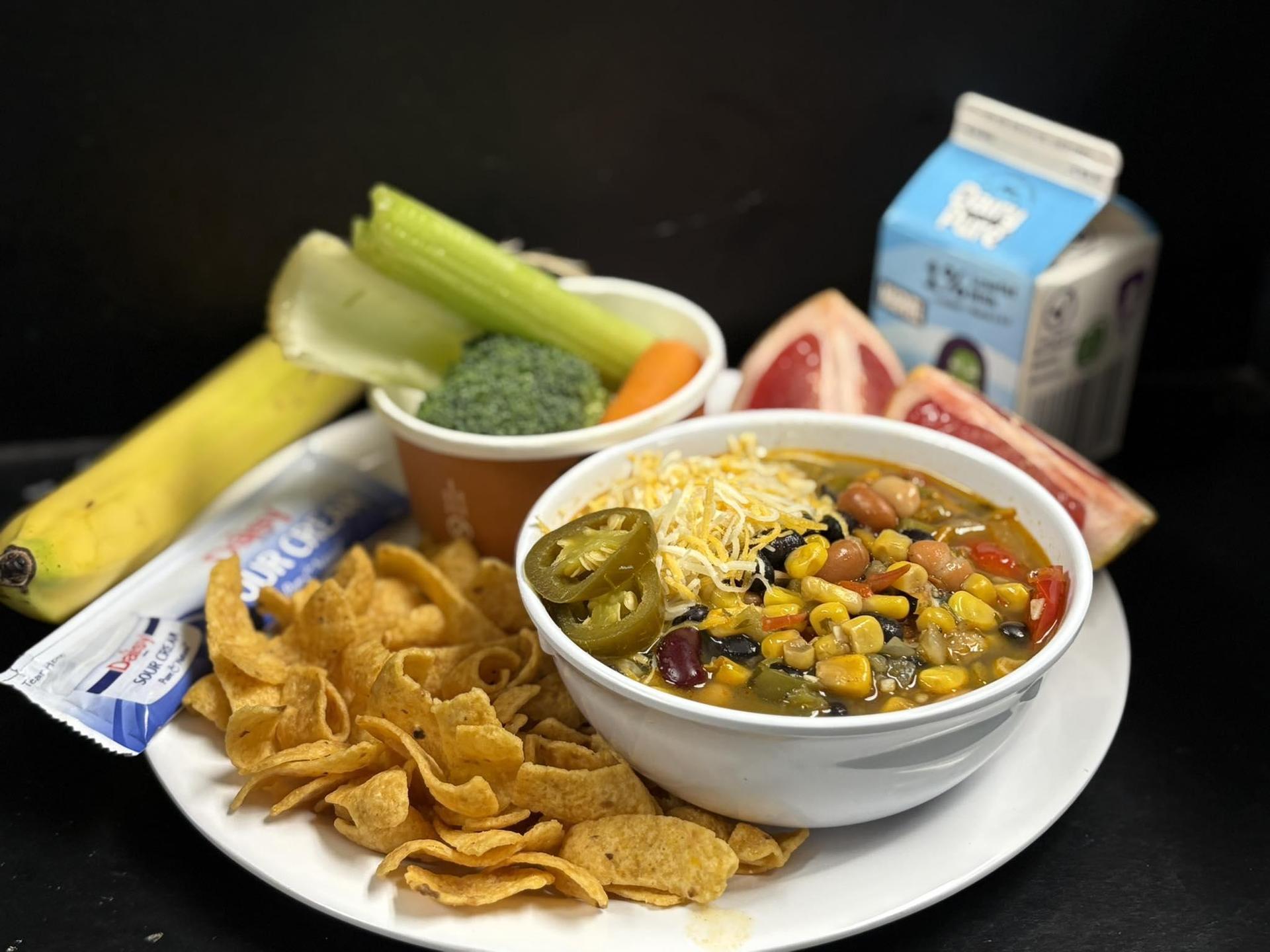 A bowl of taco soup with milk and sides
