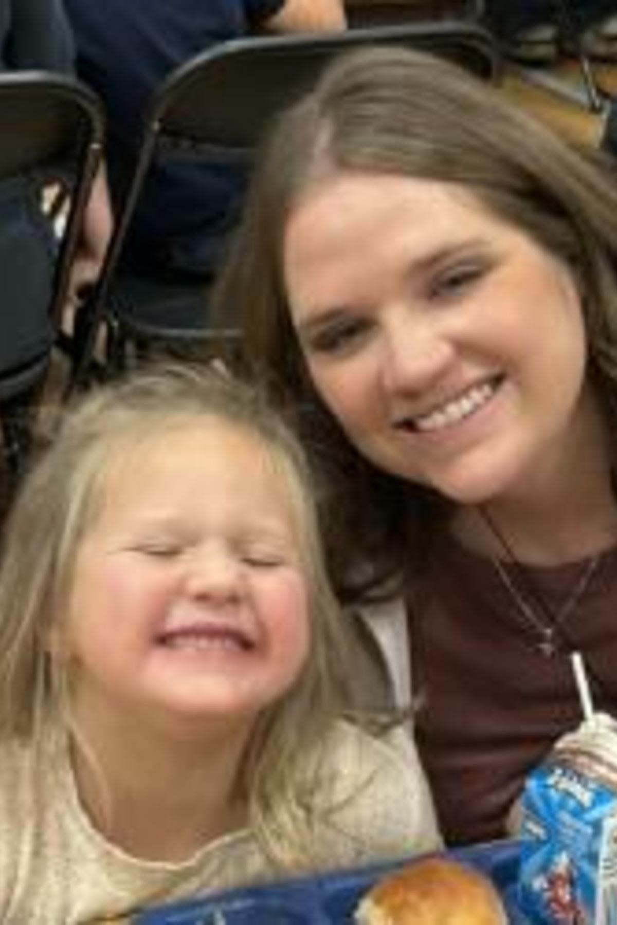A woman and a girl sitting at a table smiling happily.