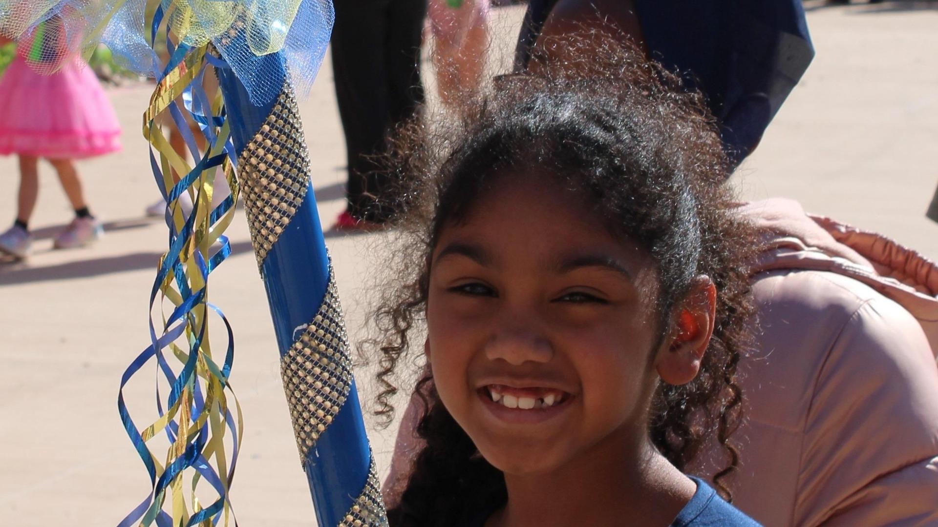 Smiling girl with curly hair standing by decorated ribbons.