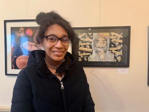 Student in front of their framed artwork on the wall