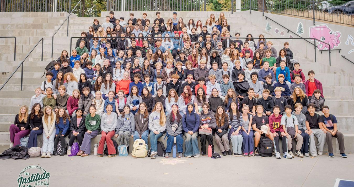 Large group of students sitting together on outdoor steps.