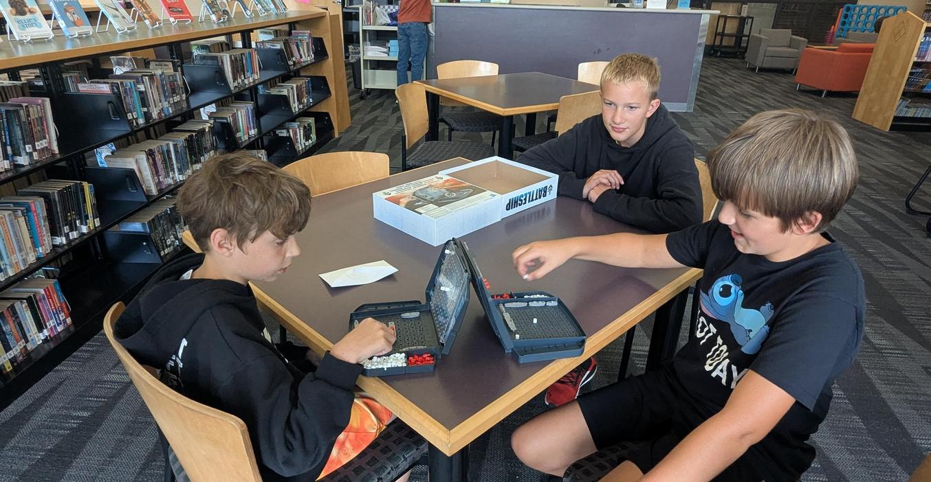 Two boys play a game of "Battleship" during the activity night event.