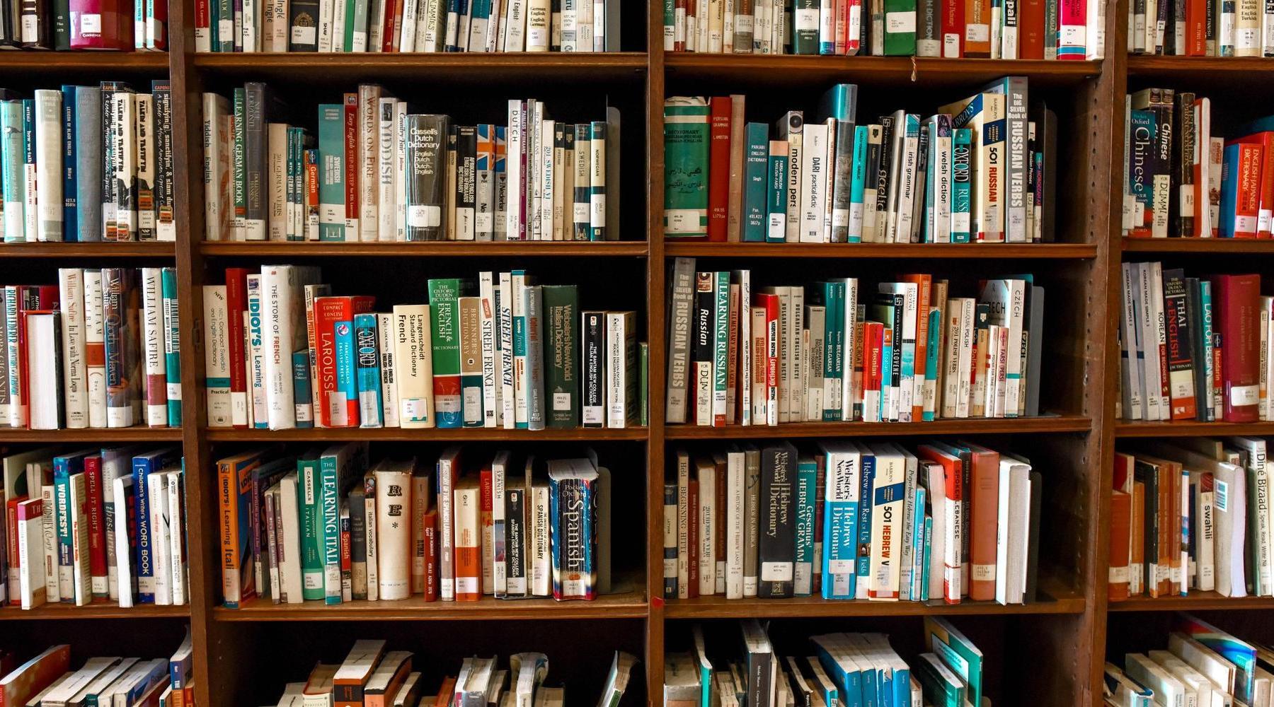 Books neatly arranged on wooden shelves in a library.