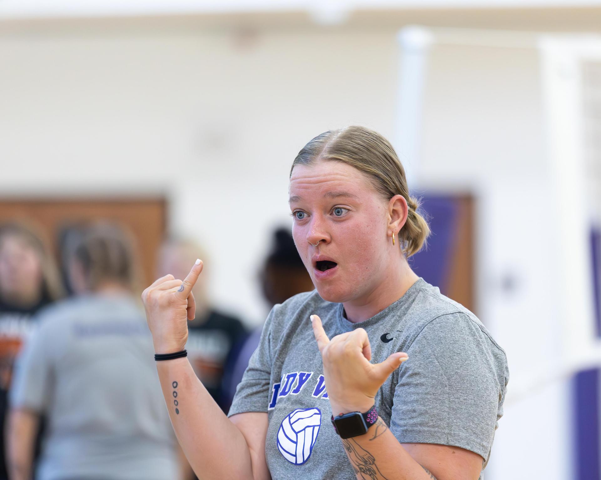 A coach gestures excitedly while explaining a play during a volleyball session.