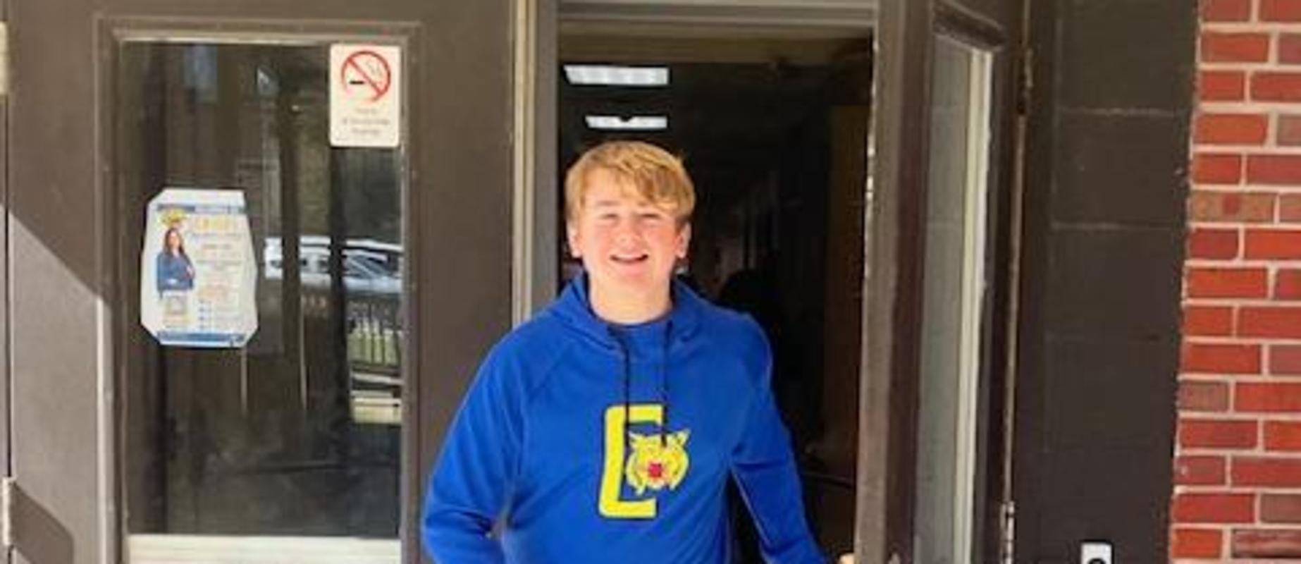 A person in a blue hoodie exiting a building.