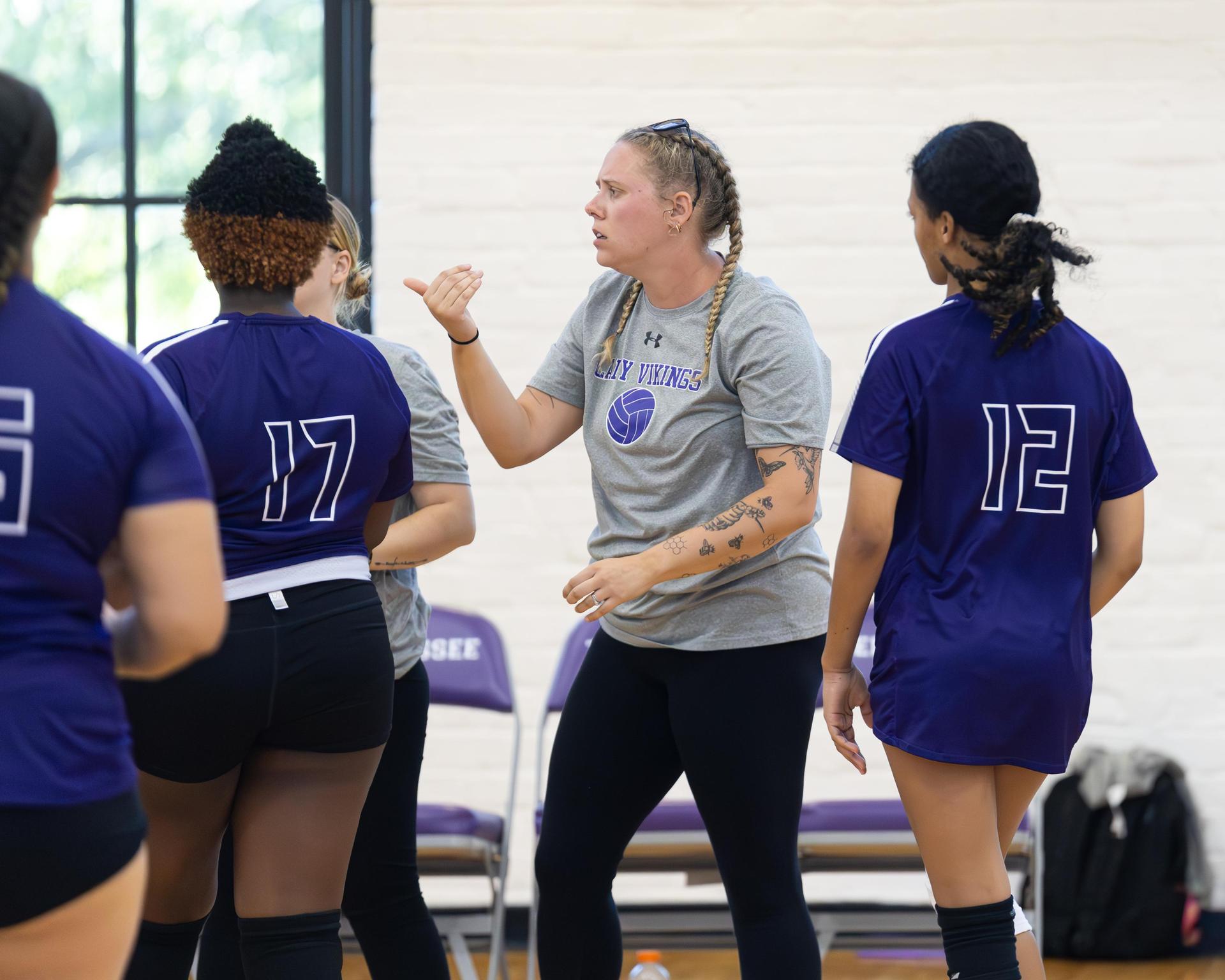 Coach giving instructions to volleyball players during practice.