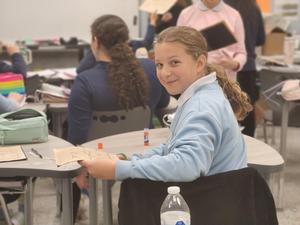 A student pauses while cutting out her project.