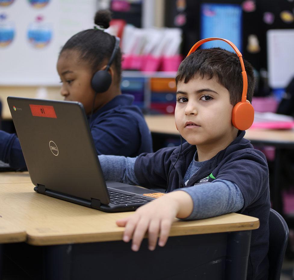 Student wearing headphones working on a laptop in the classroom