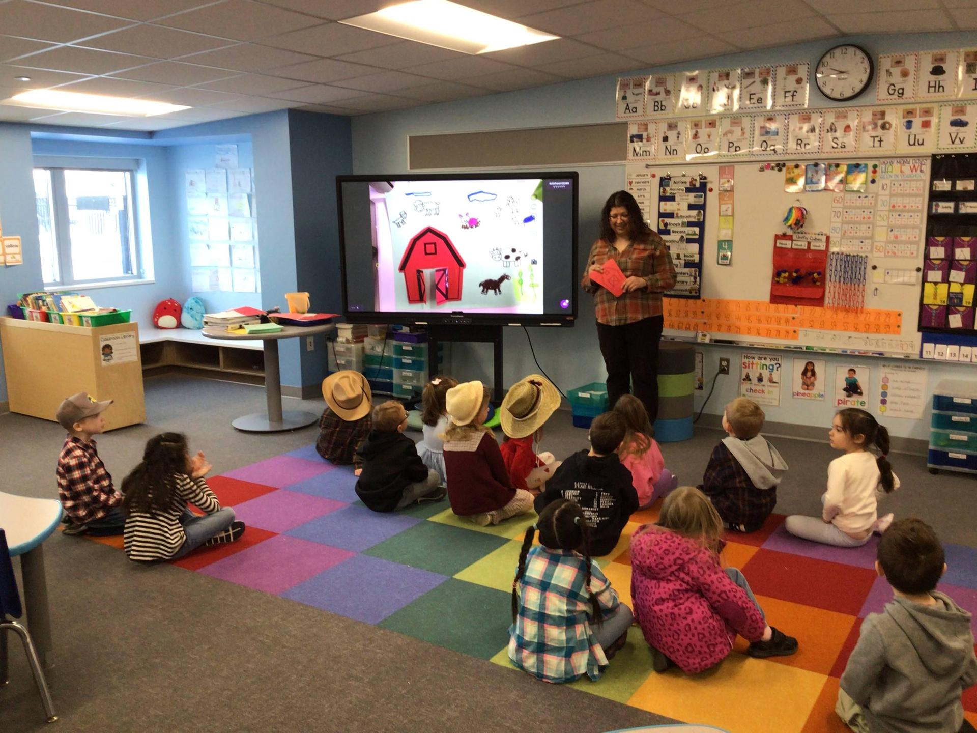 teacher in her classroom standing in front of students that are sitting on a rug