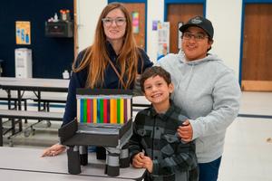 Family of three attending the Bennett Family STEM Night and posing with their project.