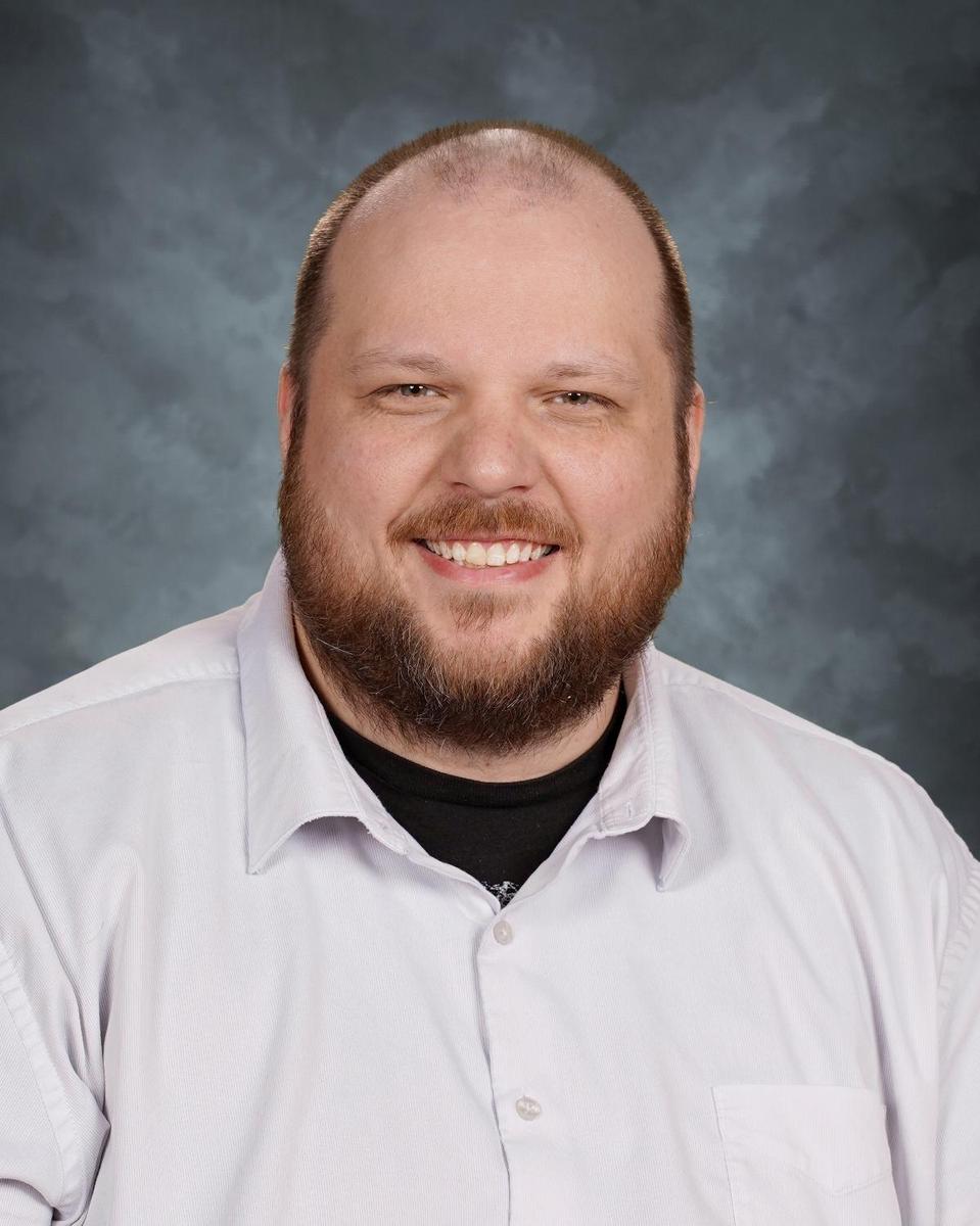 bald man with beard and mustache smiling in school photo