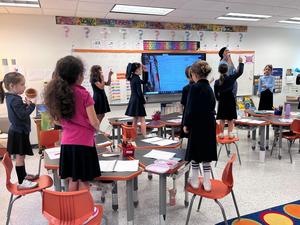 second grade girls stand on chairs while learning their first pasuk