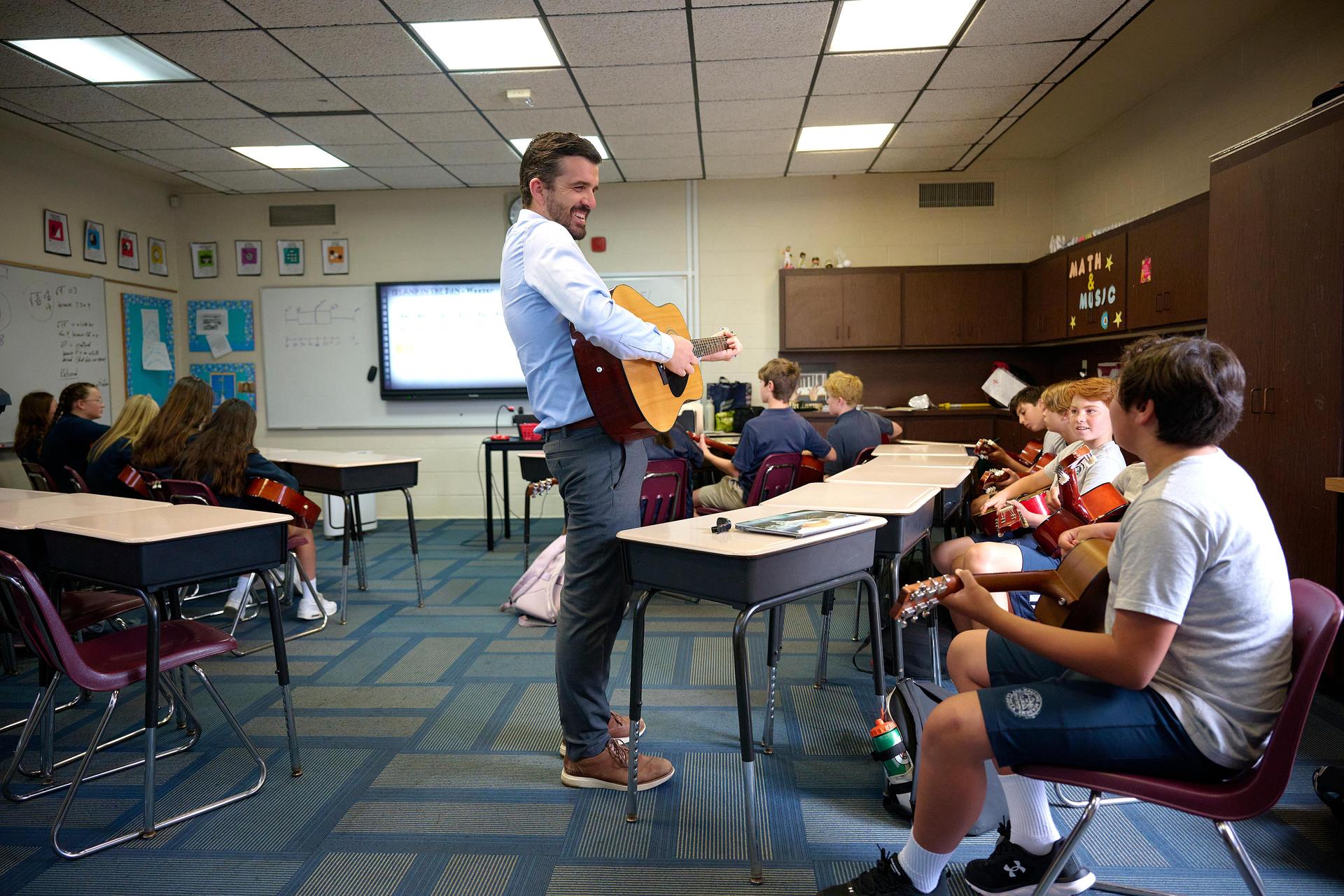 guitar teacher playing guitar with class