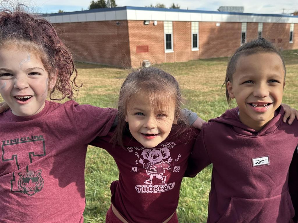 Four Tinicum students standing arm in arm in the playground behind the school.
