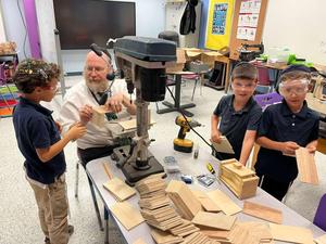 Three students use a drill on their boxes.