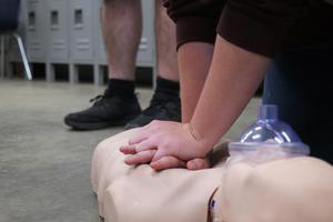 A student practicing CPR on a dummy