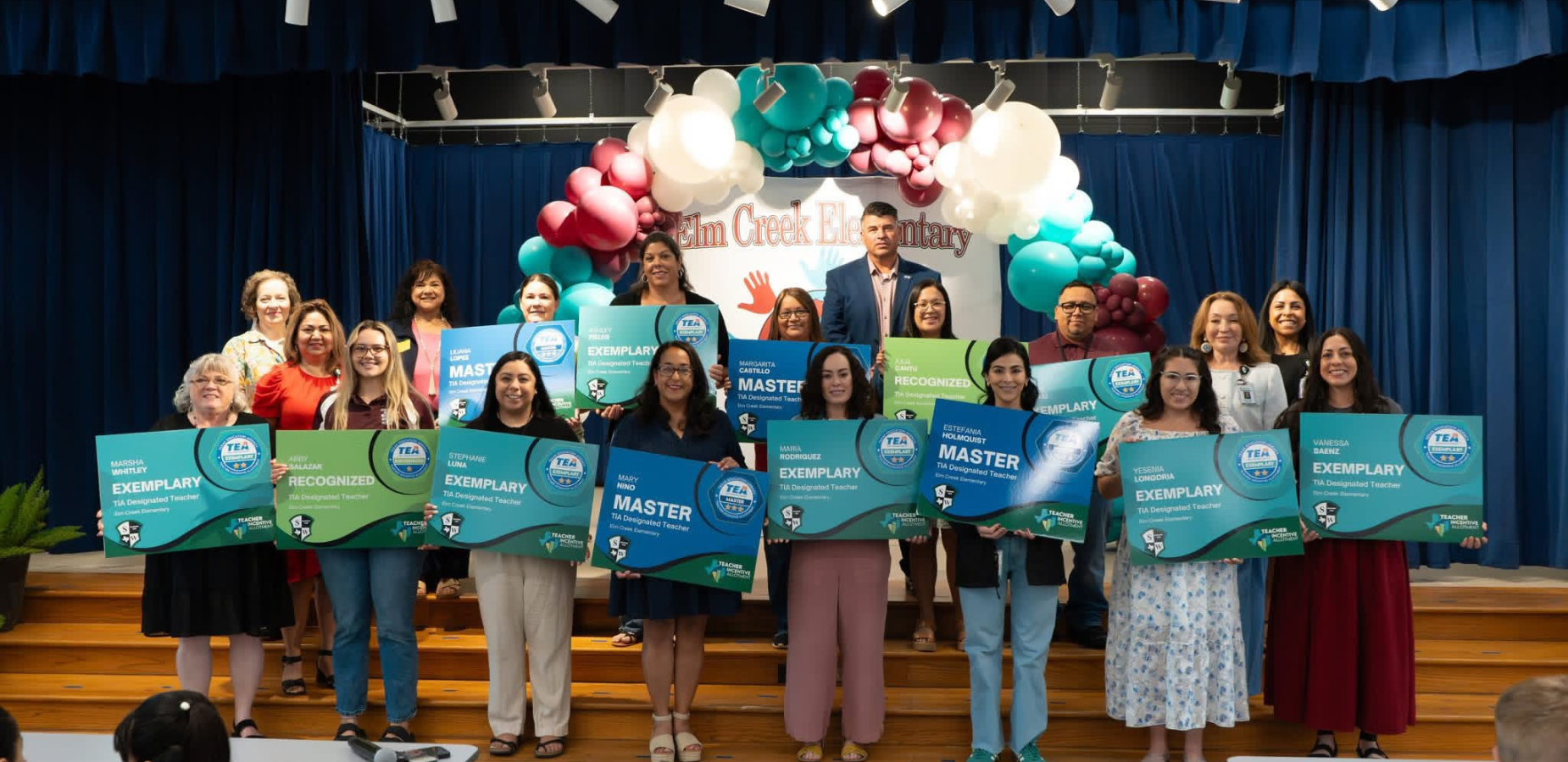 teachers standing together on stage holding award signs