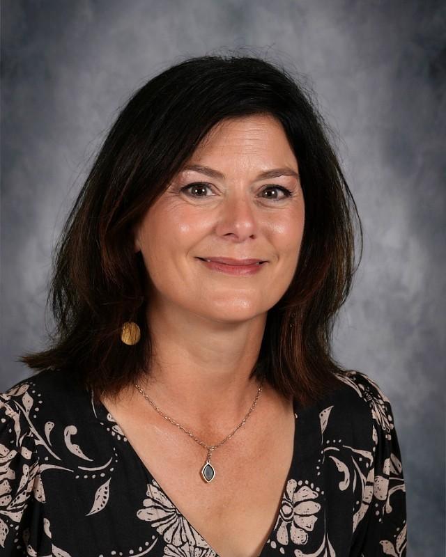 Smiling woman with dark hair in a red top against a gray background.
