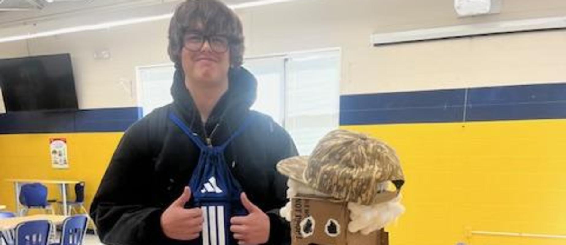 A student stands next to a cardboard figure in a classroom.