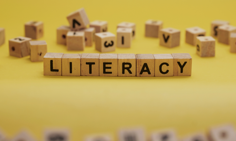 Yellow background with scrabble tiles that spell 'literacy'
