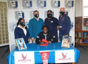 Mike Jackson signing at table with coaches