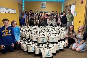Students who participated in packing the totes pose with the finished product