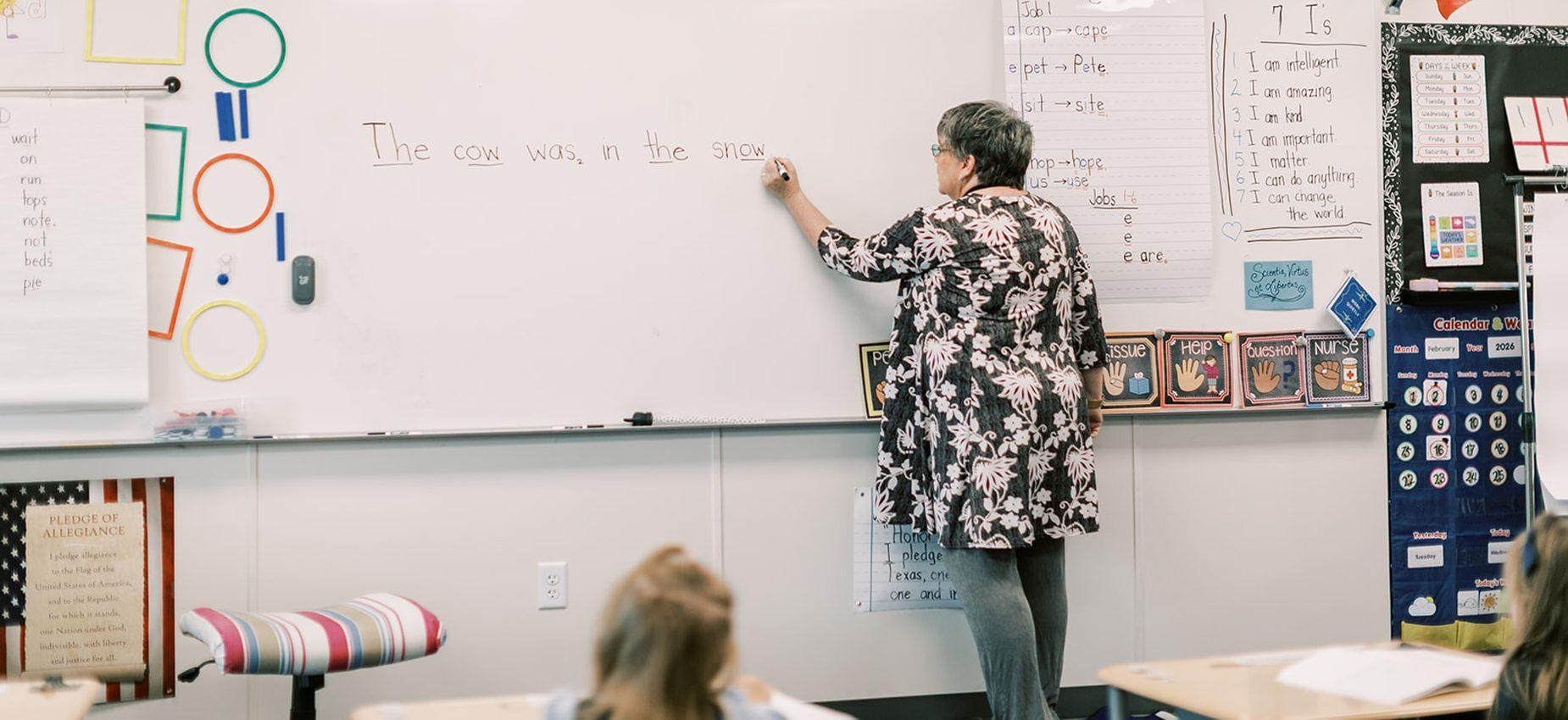 A teacher writes a sentence on the whiteboard for her elementary class at Founders Classical Academy of Bastrop