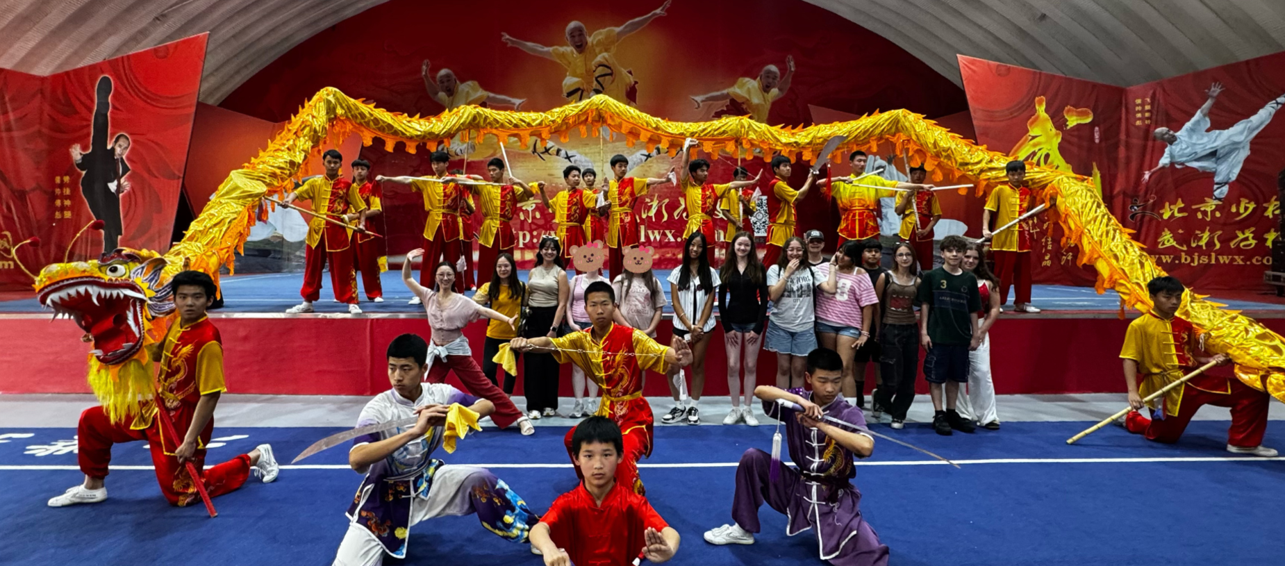 A group of performers in traditional costumes with a dragon and bow and arrow.