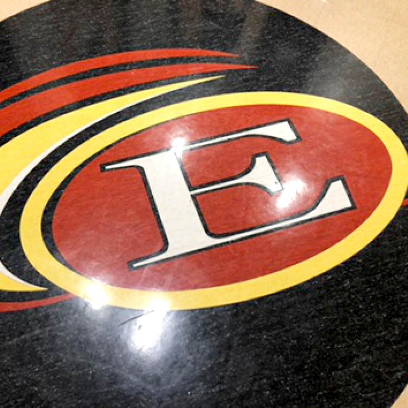 A circular floor design featuring a large red and yellow emblem with the letter E.