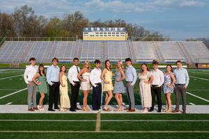 members of prom court dressed up standing on football field