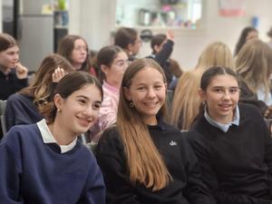 Three eighth grade students waiting to surprise their "little sisters"