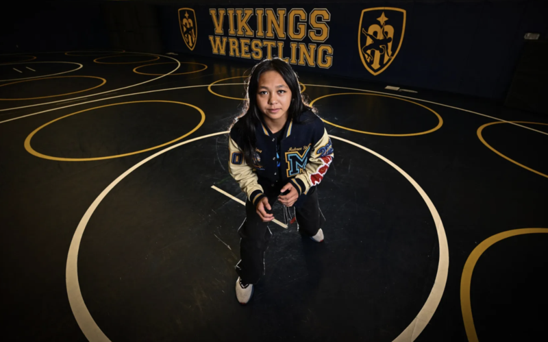 Aubree Gutierrez poses in front of Viking Wrestling sign