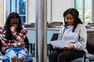 A female student reads a poem while a classmate listens