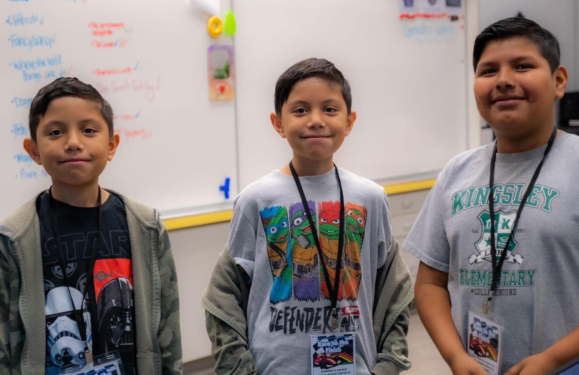 3 students pose of photo in class