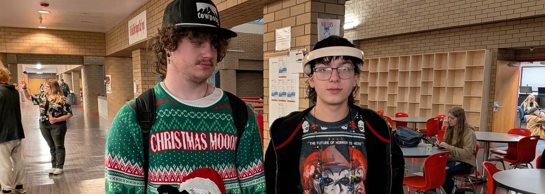 Two teenagers in festive sweaters stand together in a school hallway.
