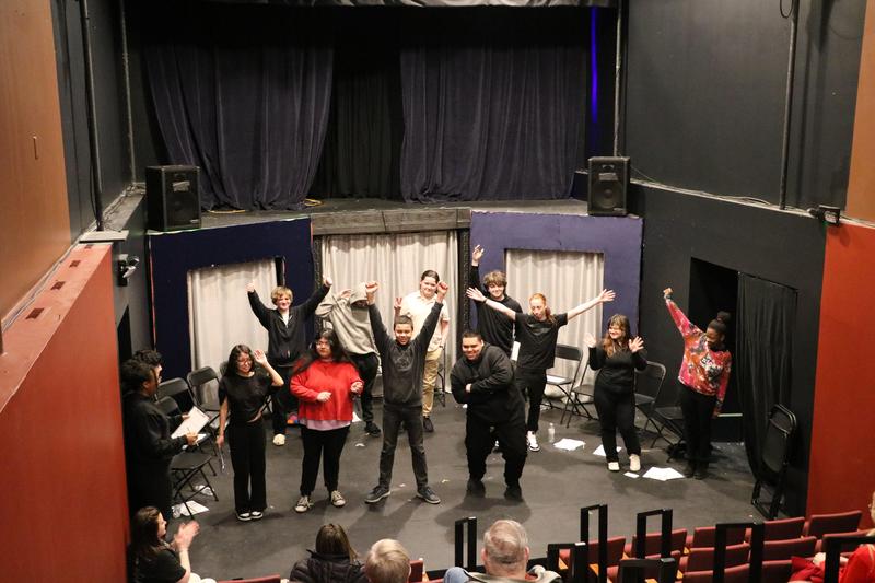 students on stage spaced out and bowing