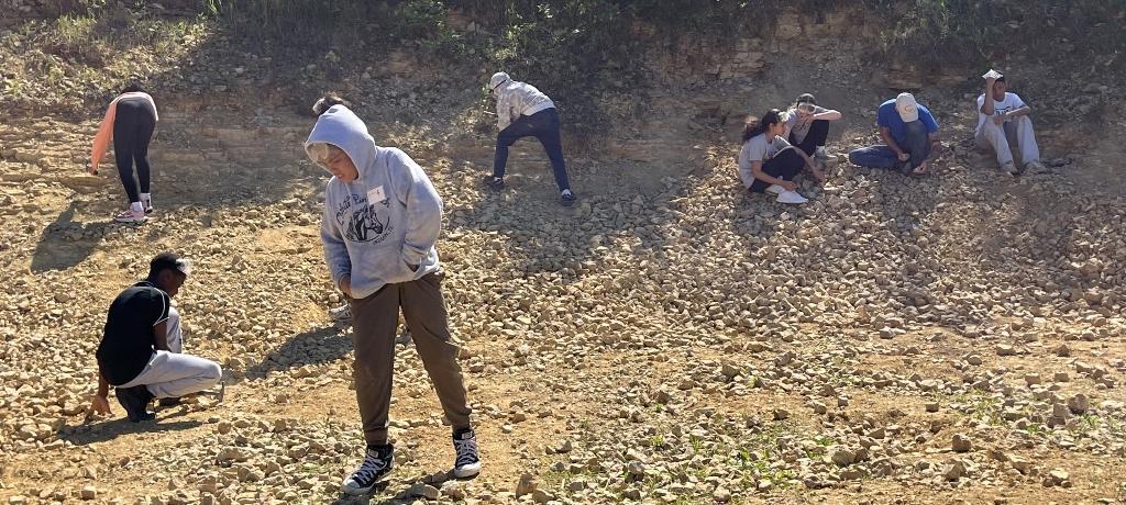 students use hammers to search rocks for fossils