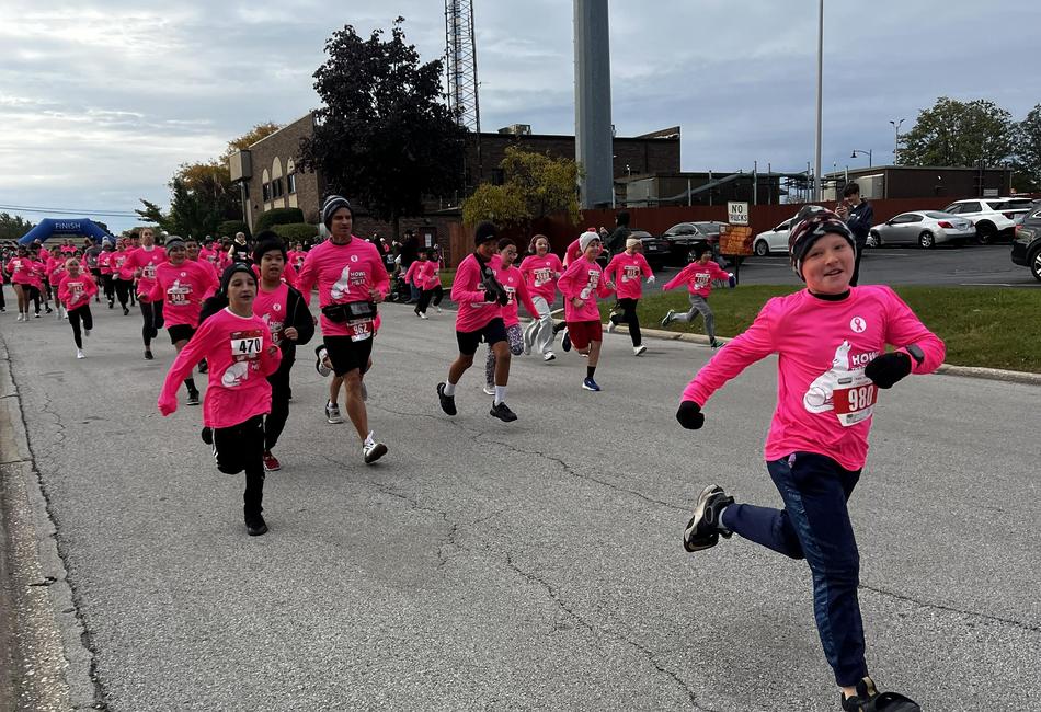 Runners in pink shirts participating in a race on a street.