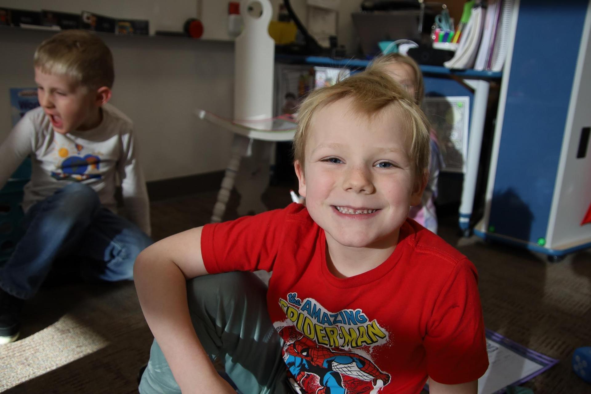 elementary school boy smiling at the camera in a classroom