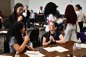 Students sit at a table with an adult volunteer